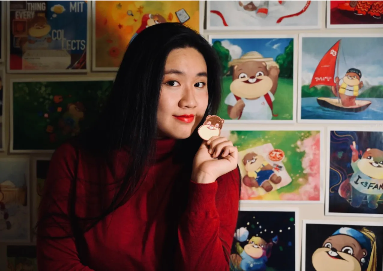 Margaret Zheng holding a small Wide Tim in front of a wall of Wide Tim art